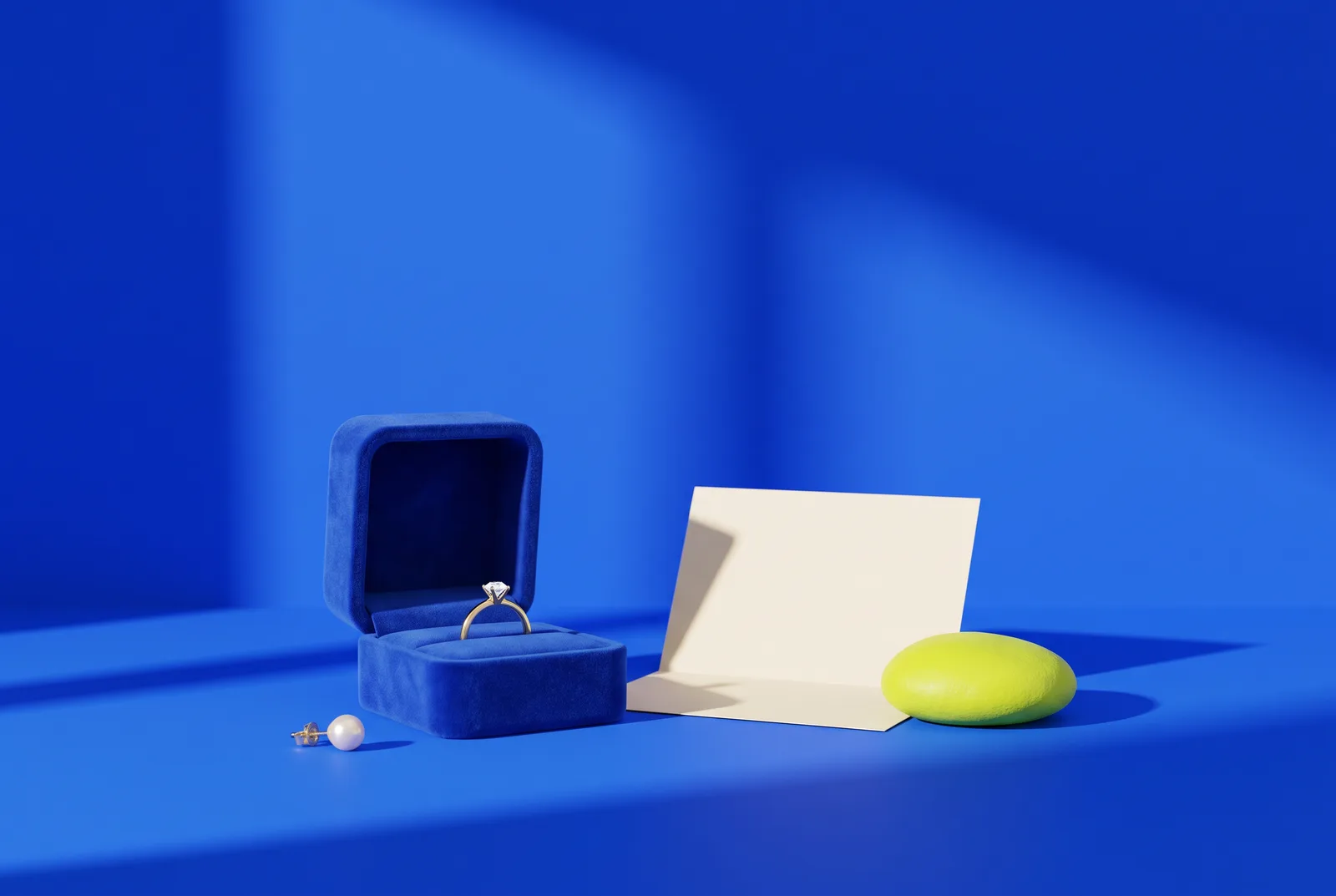 A blue velvet ring box with a gold ring, a pearl earring, a blank certificate card and a lime pebble, the setting for jewelry store QR codes.