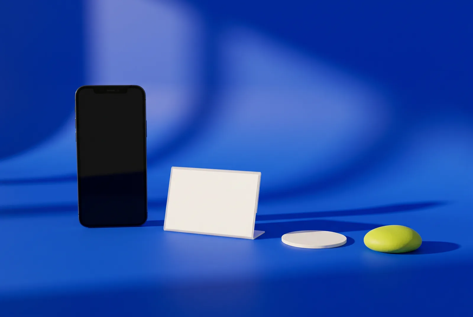 QR code vs NFC: an upright smartphone, a white counter sign stand with a blank card, a round NFC tag and a lime pebble on a cobalt blue surface.