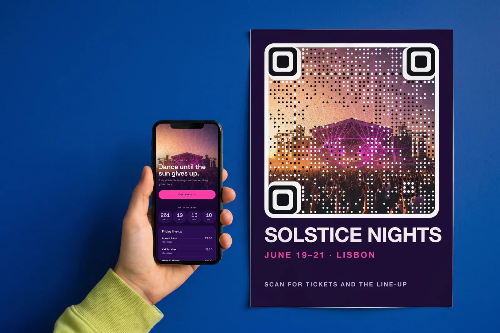 A hand holds a phone showing an event's ticket page in front of a poster whose artwork is an AriaQR code.