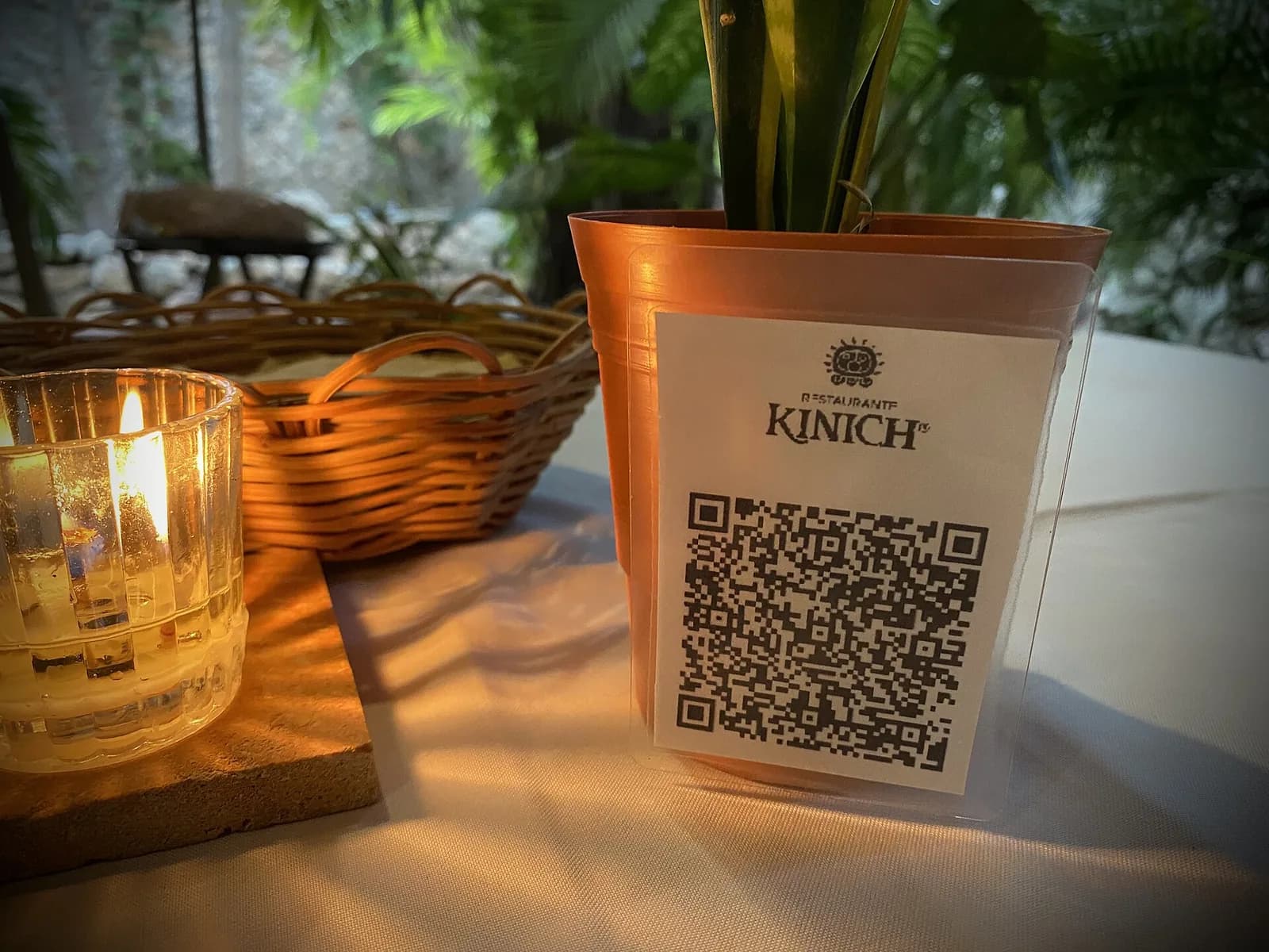 A QR code menu card standing on a candle-lit restaurant table.